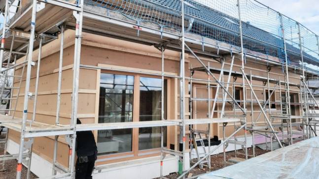 Holzhaus von außen in der Fertigstellung mit Gerüst