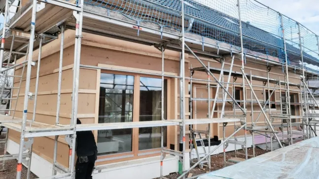 Holzhaus von außen in der Fertigstellung mit Gerüst