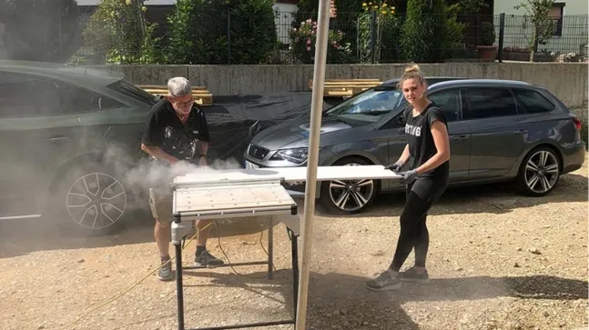 Kleiner Junge mit ins Gesicht gezogenem Hut an einen Heuballen anlehnend auf einer Strohwiese