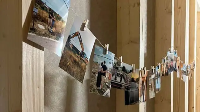 Verschiedenste Bilder von Familie, Freunden, Baustellenfahrzuge und mehr, hängen mit Wäscheklammern befestigt an Holzpfosten