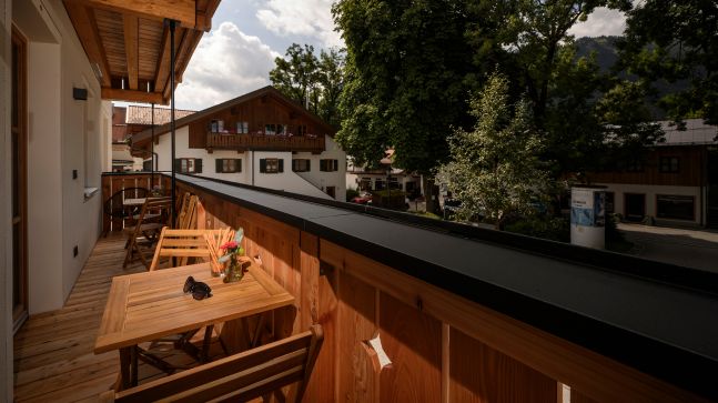 Balkonterasse mit Aussicht auf die Stadt , Terasse hat mehrere Stühle und Tische mit Blumen etc darauf